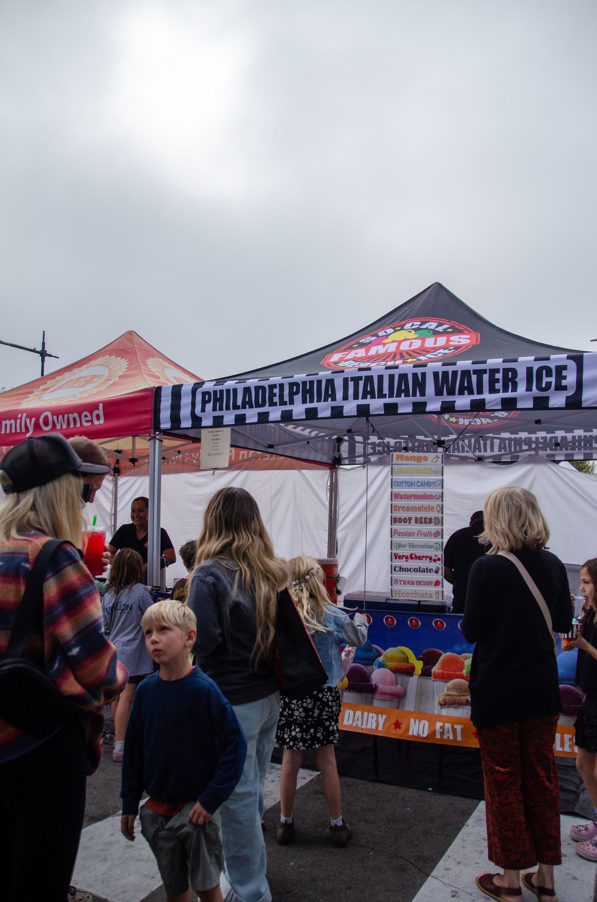 People stand in a line at a tent booth labeled 