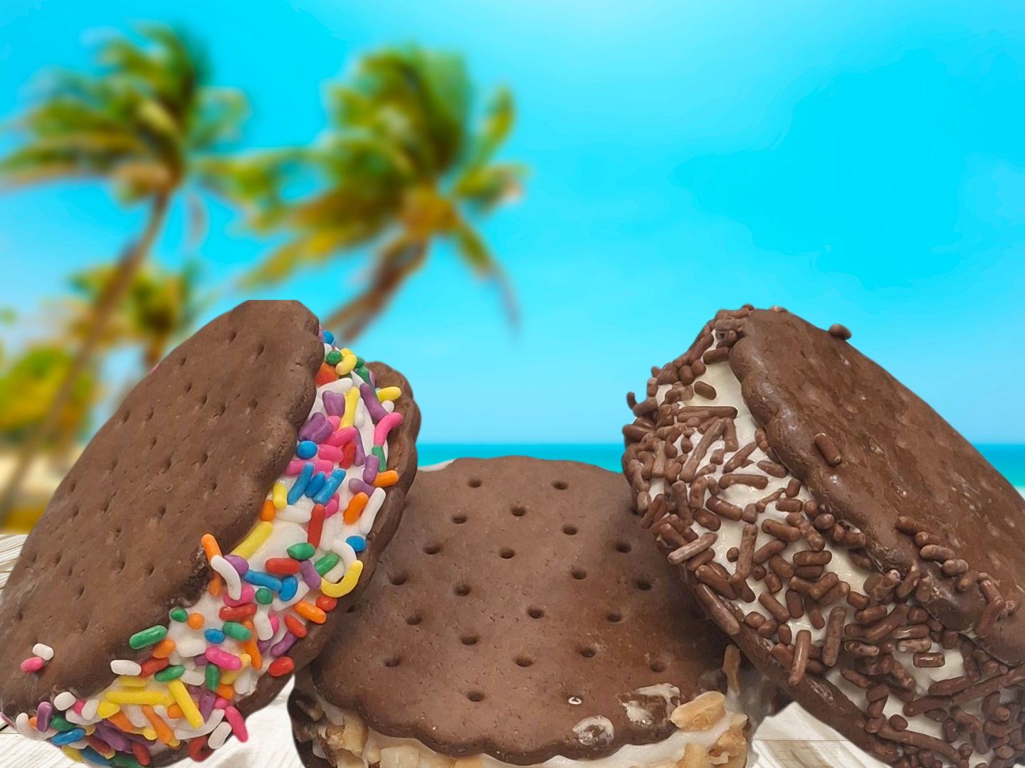 Three ice cream sandwiches—one with rainbow sprinkles, one plain, and one with chocolate sprinkles—against a beach backdrop.