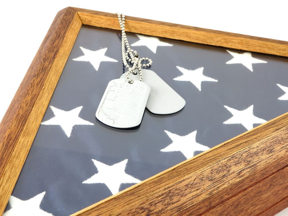 Silver dog tags on a star-patterned fabric framed by a wooden border