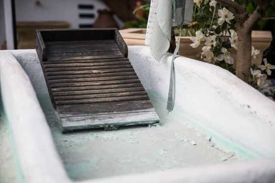A white sink with a wooden washboard in it