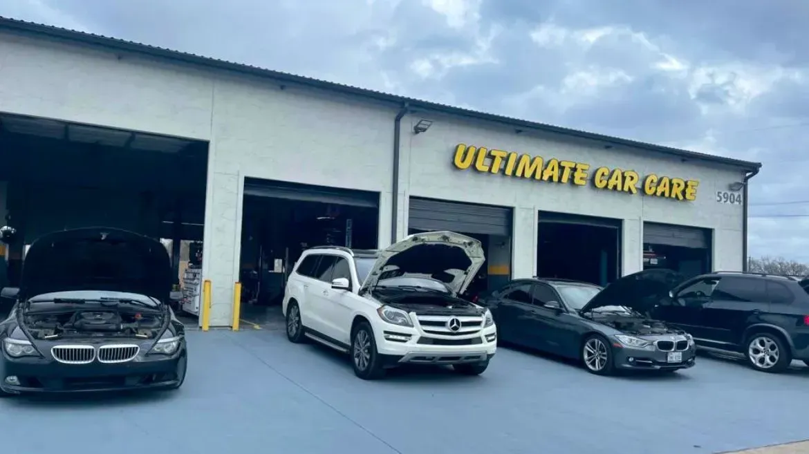 Cars with open hoods in front of an auto repair shop with 