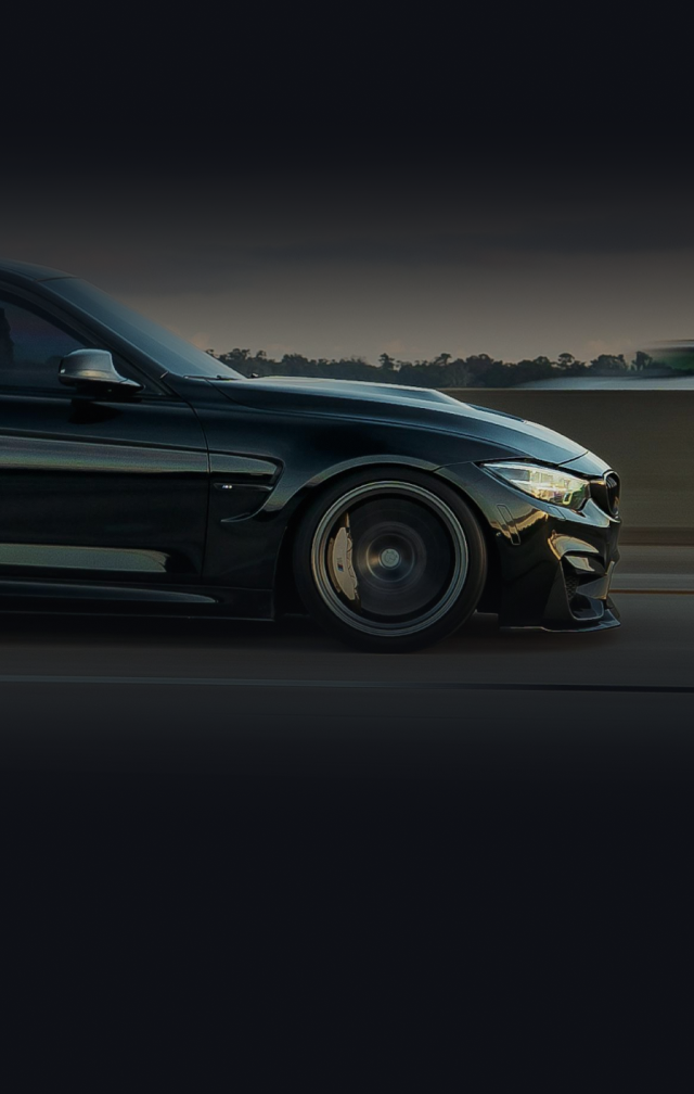 Black BMW car driving on a dark road, partially visible with a blurry background. | Ultimate Car Care
