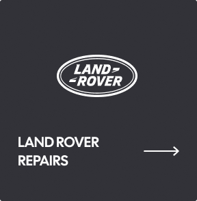 A dark gray sign with the Land Rover logo above the text 