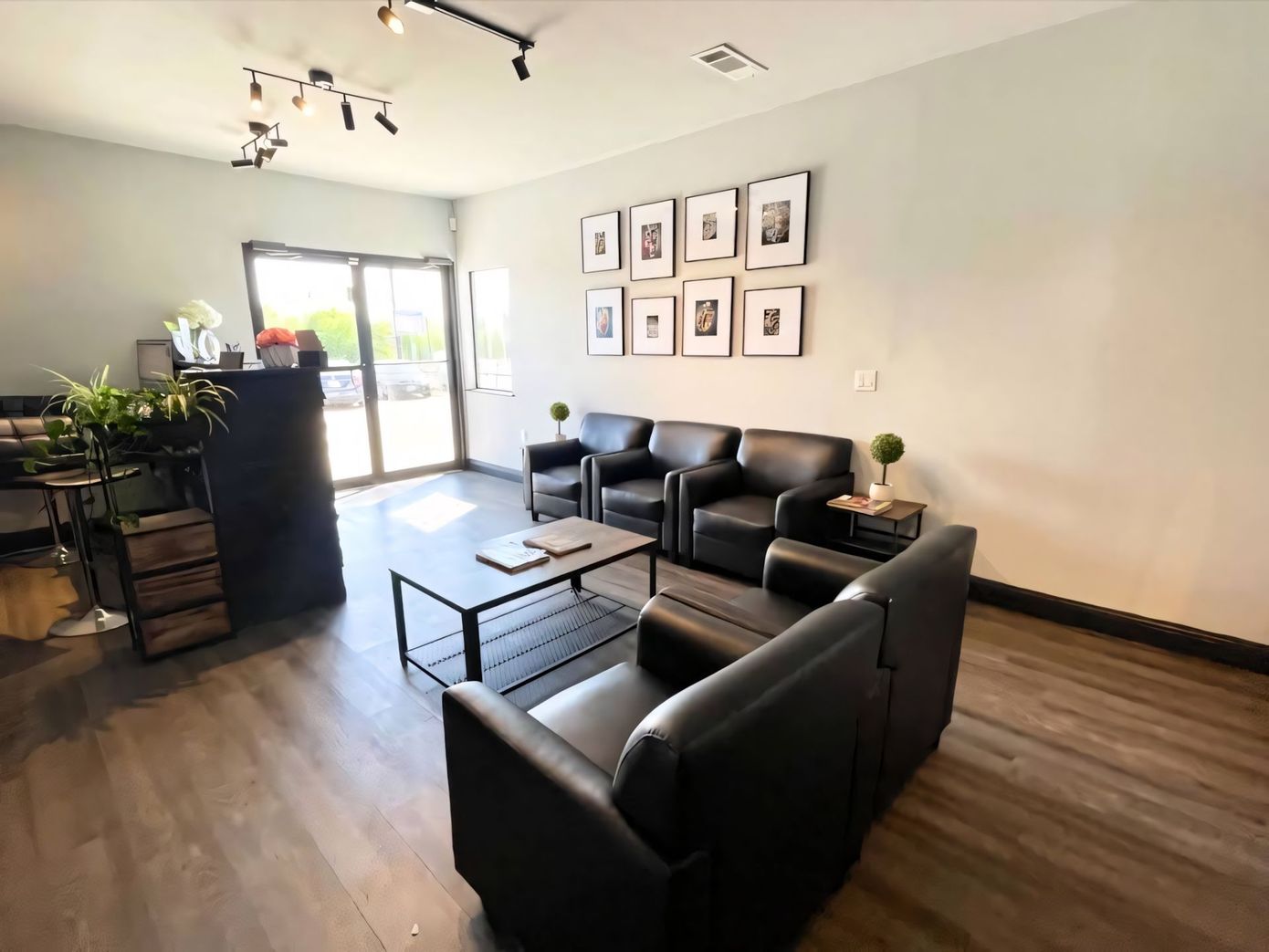 A waiting area with black leather chairs, a coffee table, and a wall gallery of framed black and white photos.
