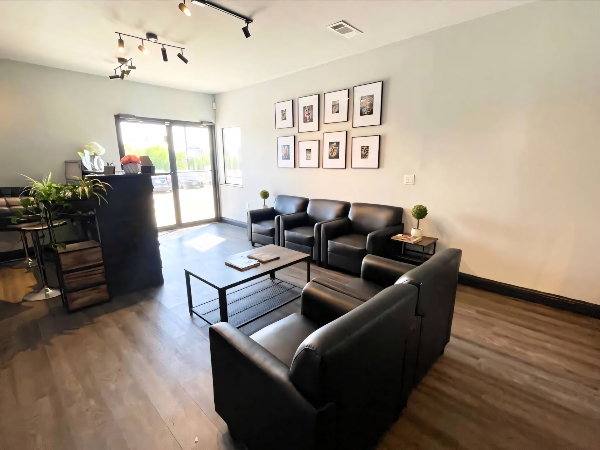 Reception area with black leather seating, a desk, framed photos, and a doorway. | Ultimate Car Care