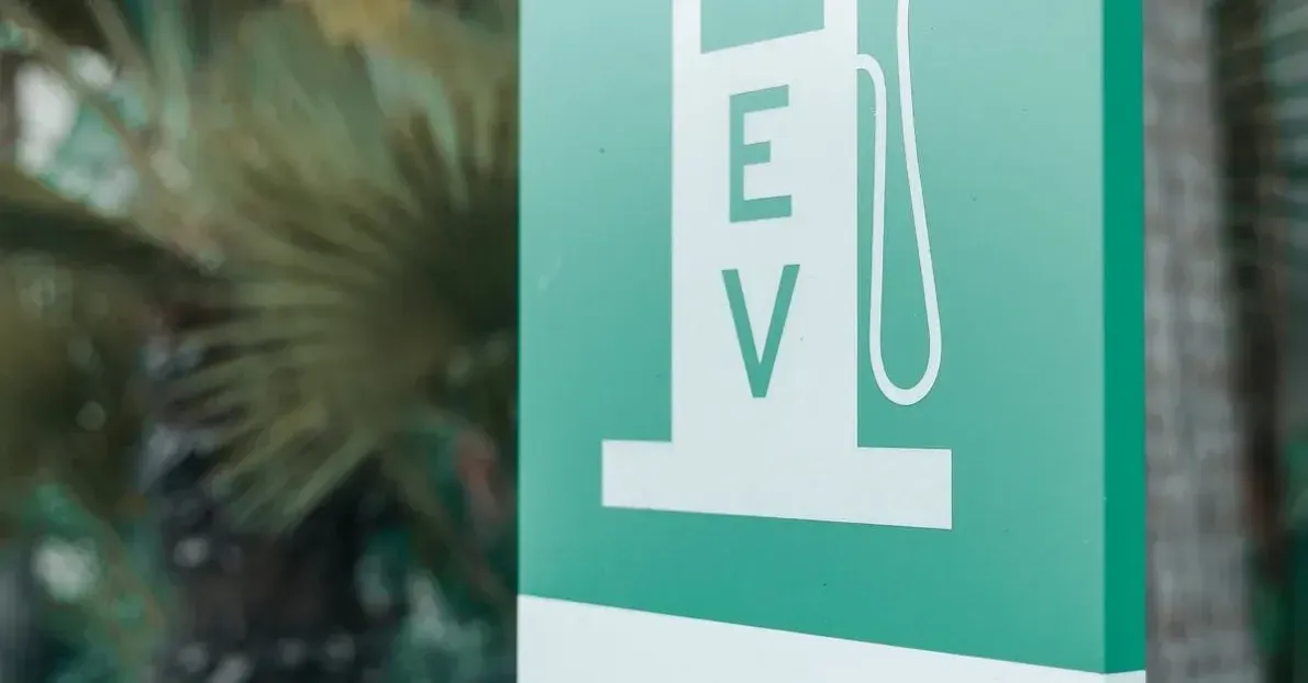 Green sign with EV charging symbol; outdoors. | Ultimate Car Care