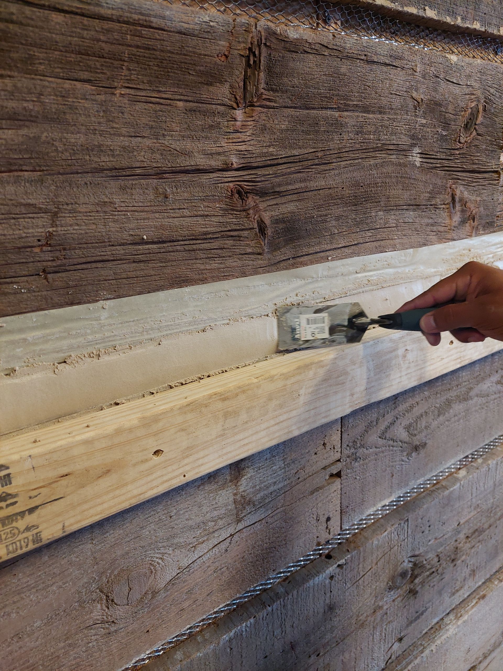 a person is painting a wooden wall with a brush .