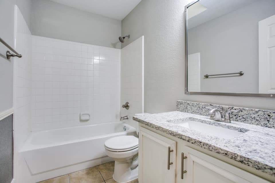 a bathroom with a sink , toilet , bathtub and mirror .