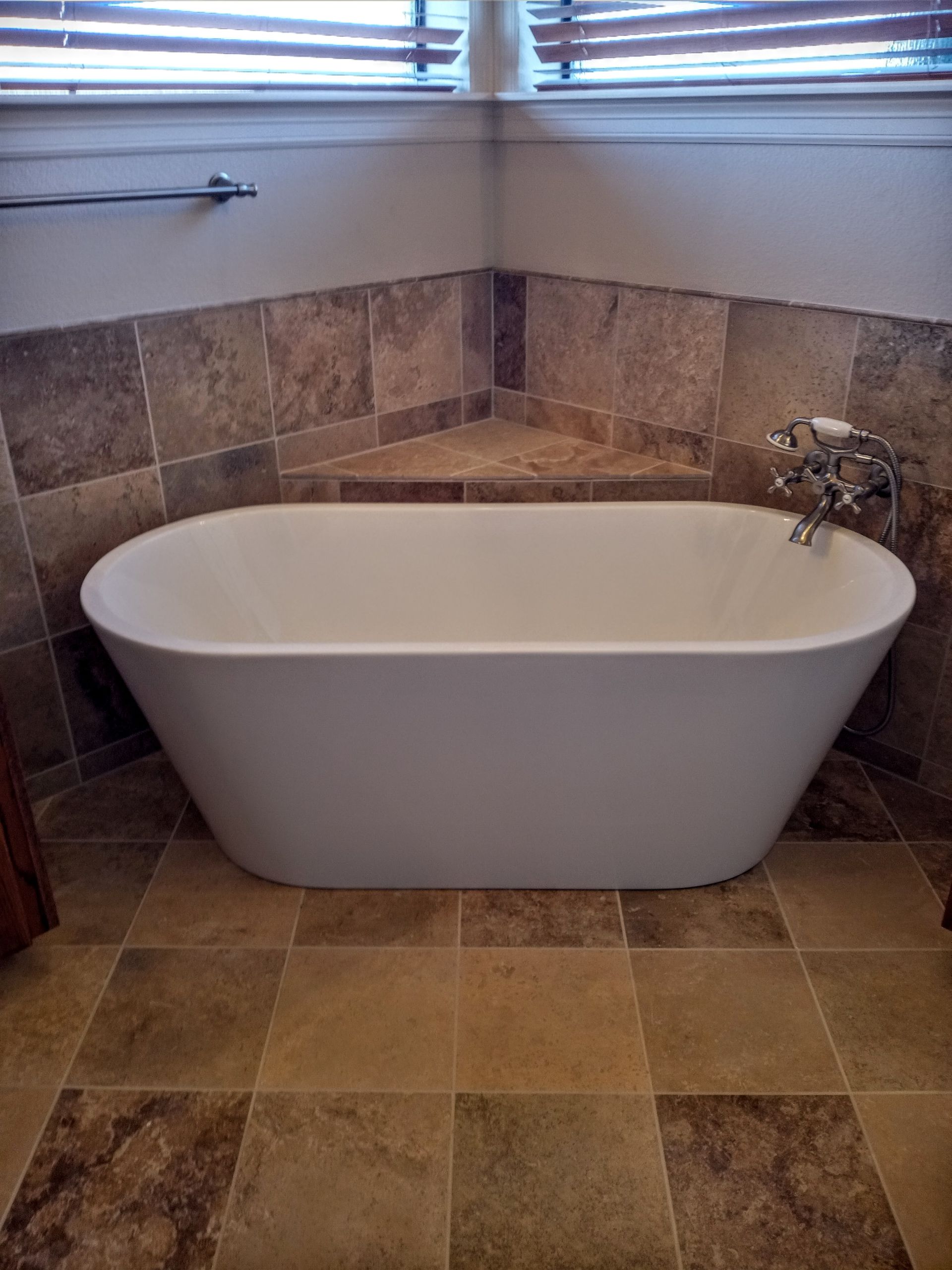 a bathtub is sitting on a tiled floor in a bathroom next to a window .