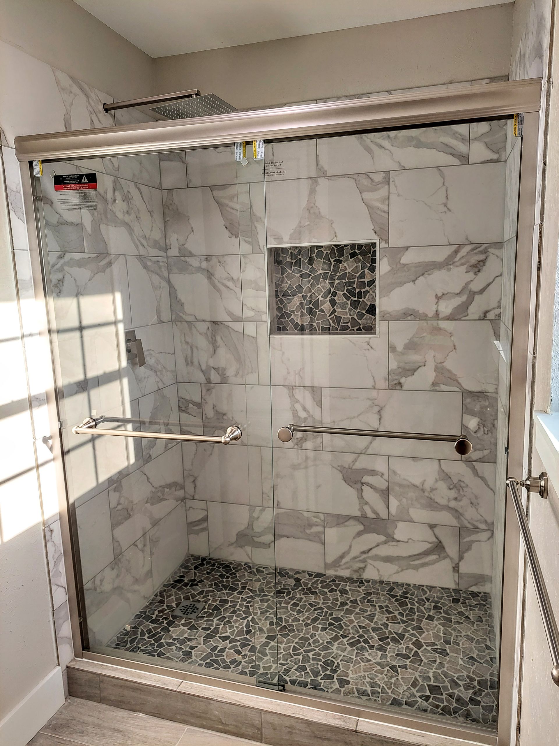 a bathroom with a walk in shower with a sliding glass door .