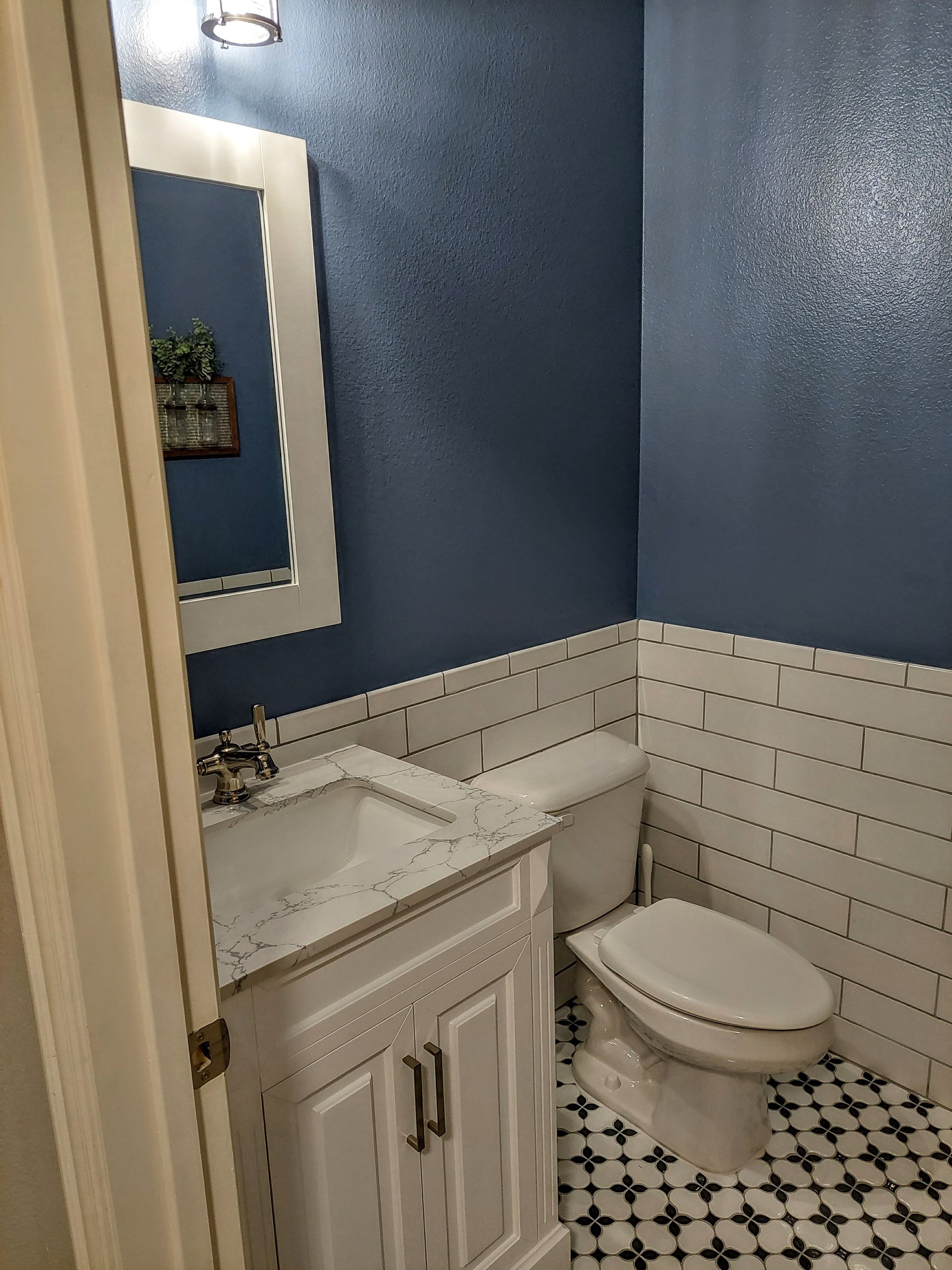 a bathroom with a sink , toilet , mirror and blue walls .