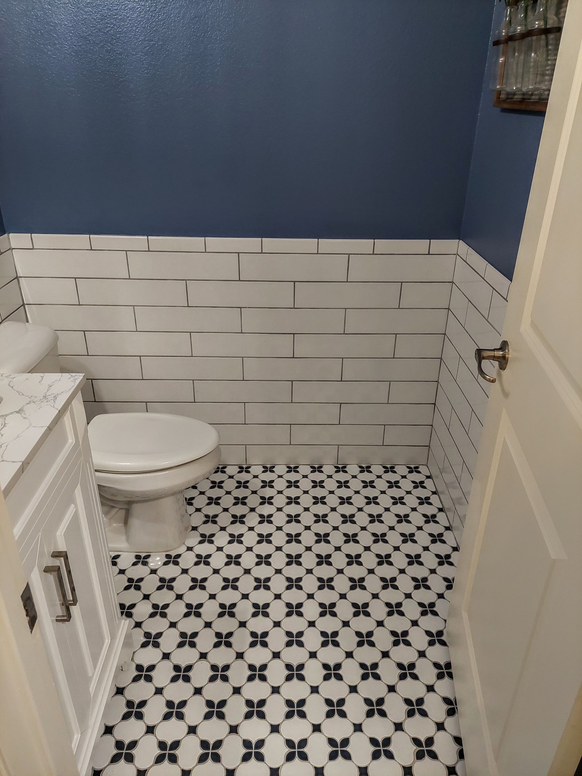 a bathroom with a toilet , sink , and black and white tile floor .