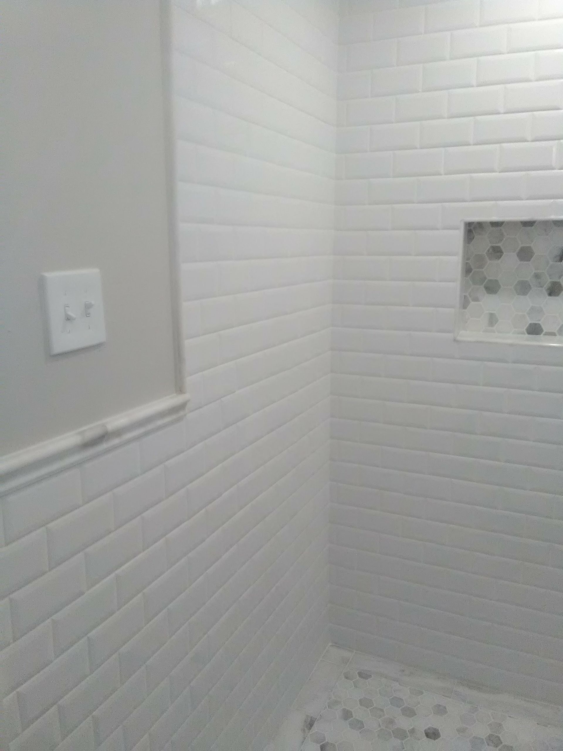 a bathroom with white brick walls and a tiled floor .