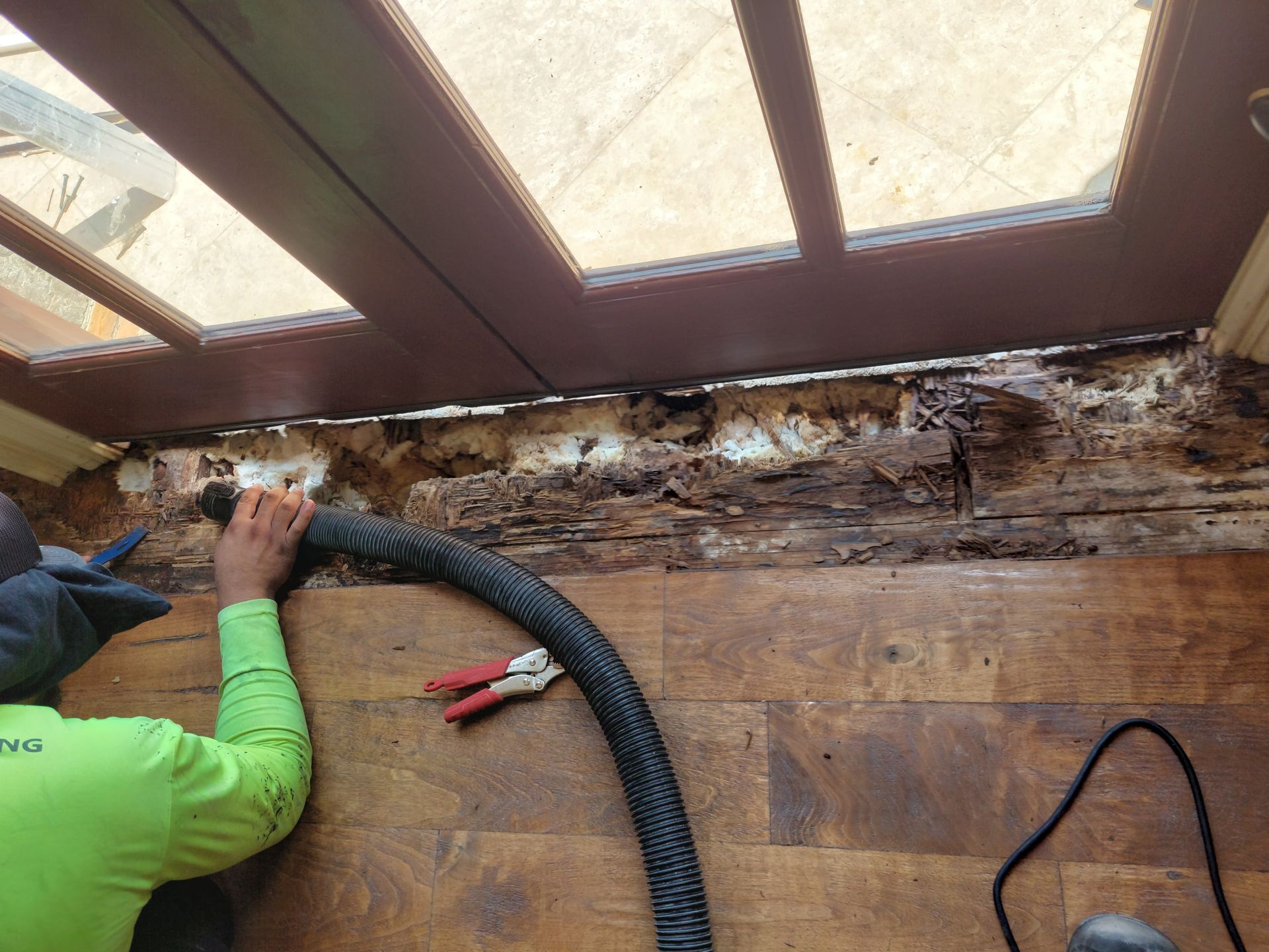 a man is using a vacuum cleaner to clean a wooden floor .