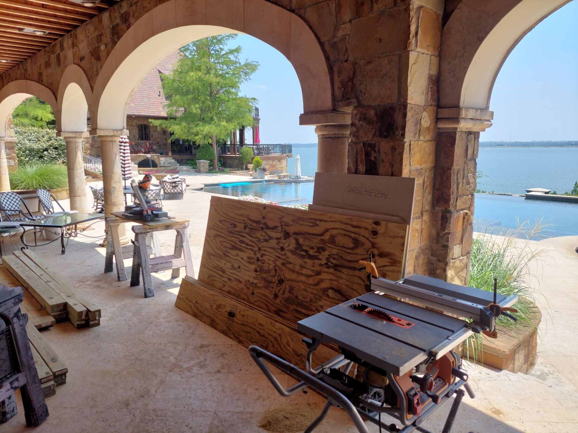 a table saw is sitting under an archway next to a pool .