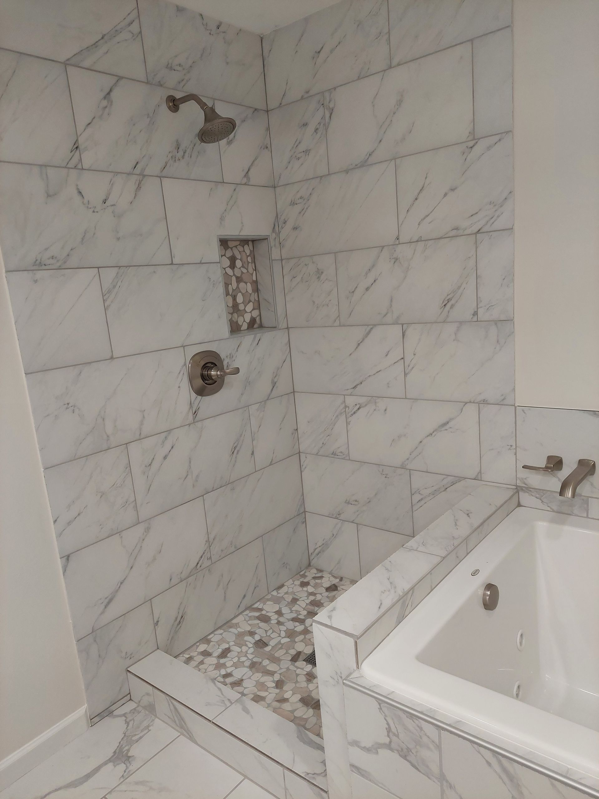 a bathroom with a tub , shower , and marble tiles .