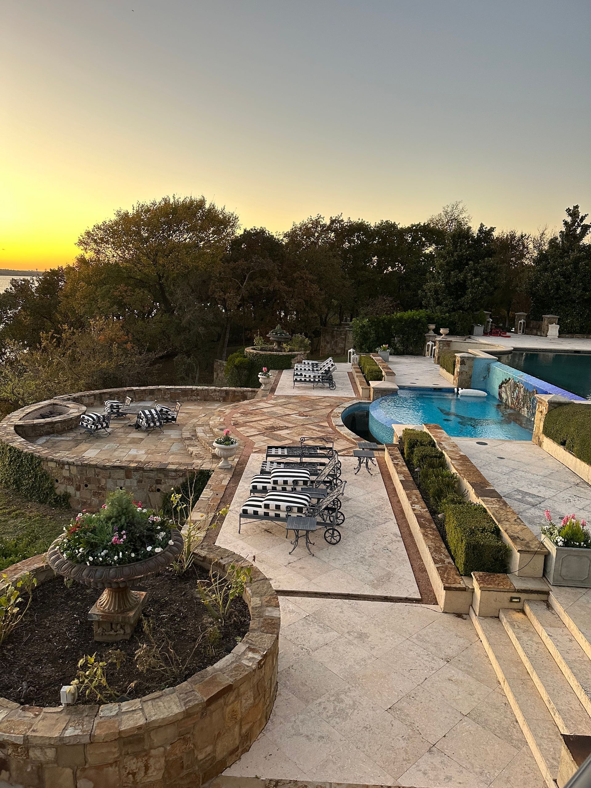 a large backyard with a swimming pool and a fire pit at sunset .