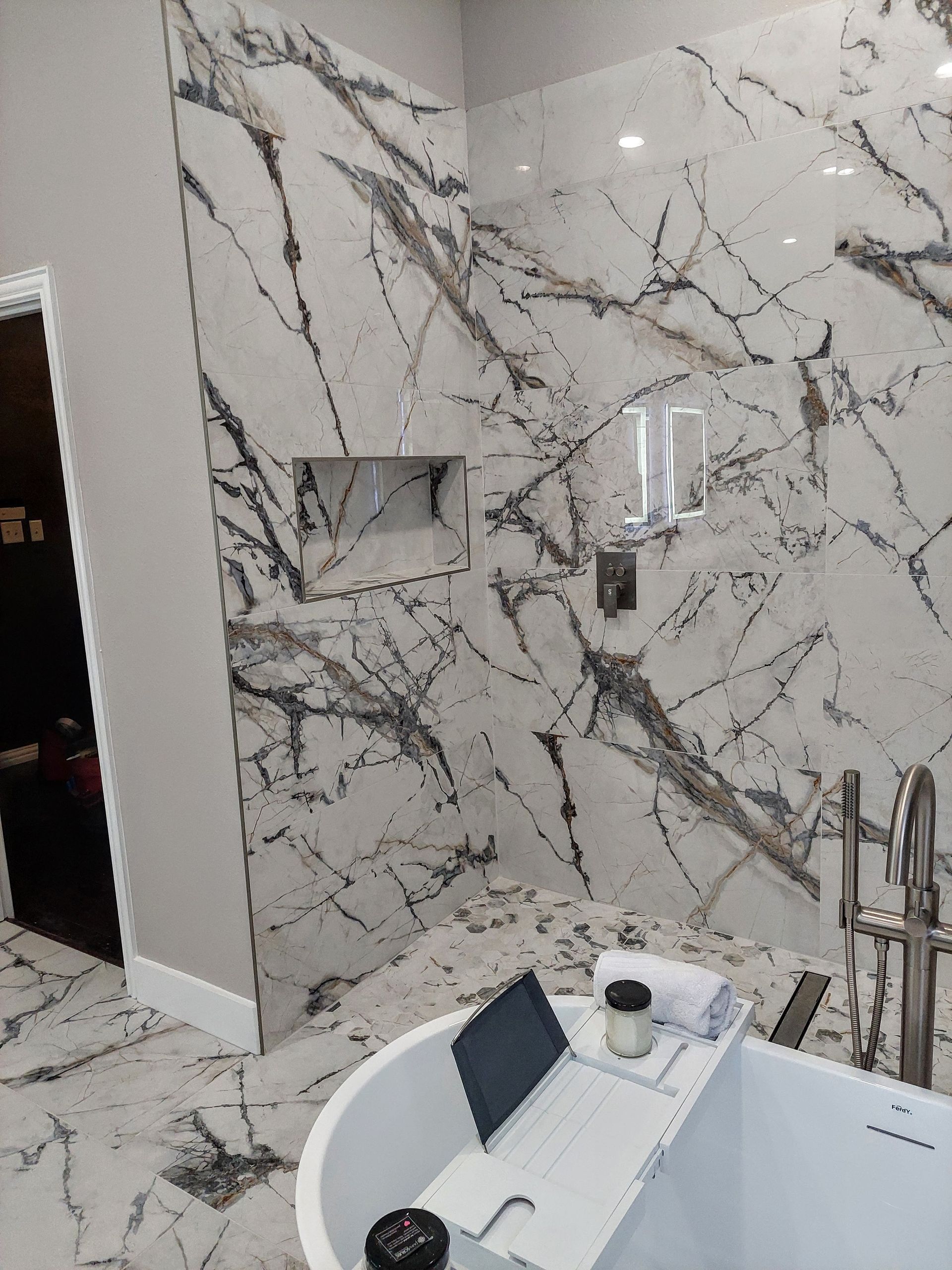 a bathroom with a bathtub and a laptop on a bathtub tray .