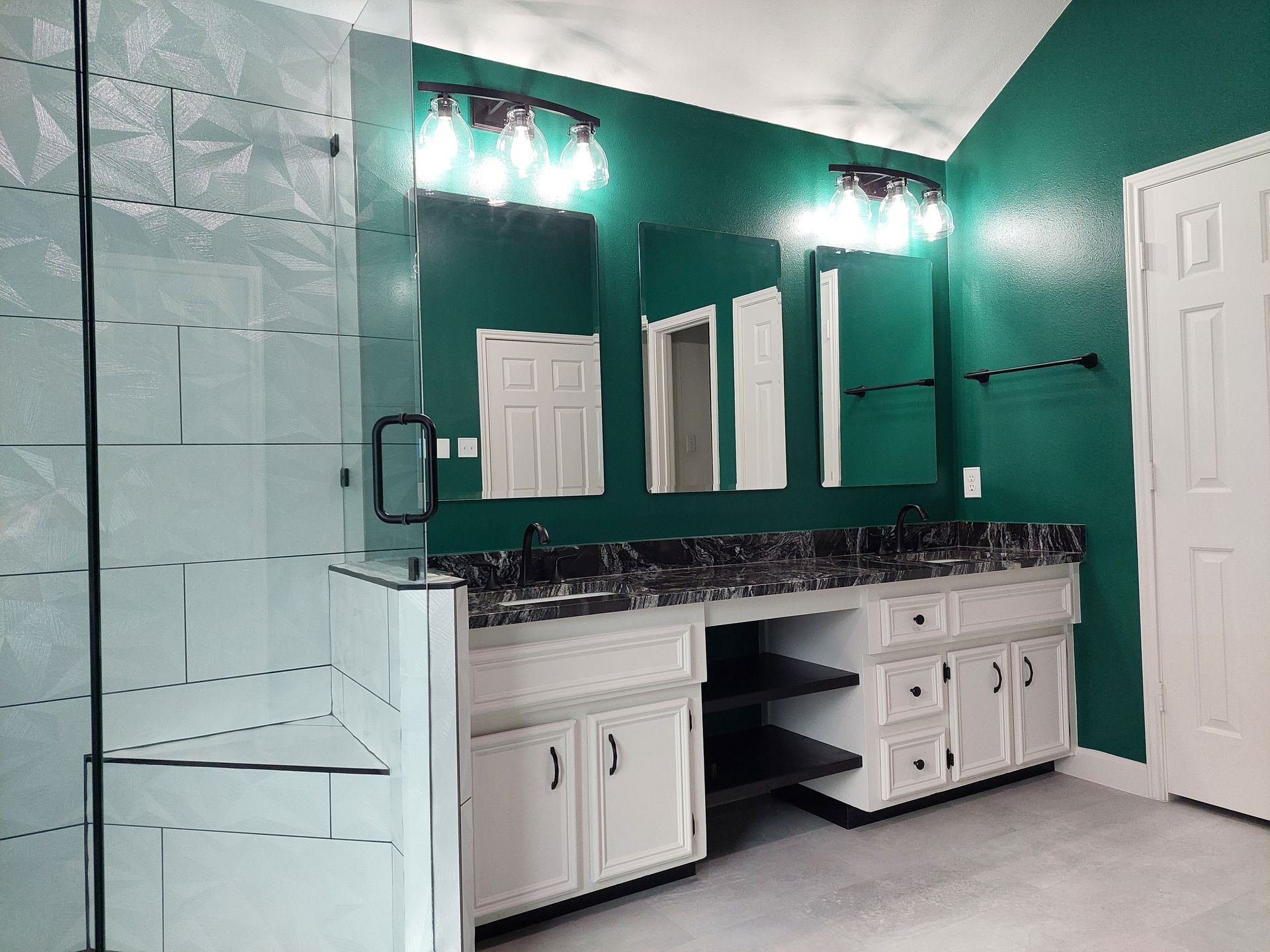 a bathroom with two sinks , two mirrors and a walk in shower .