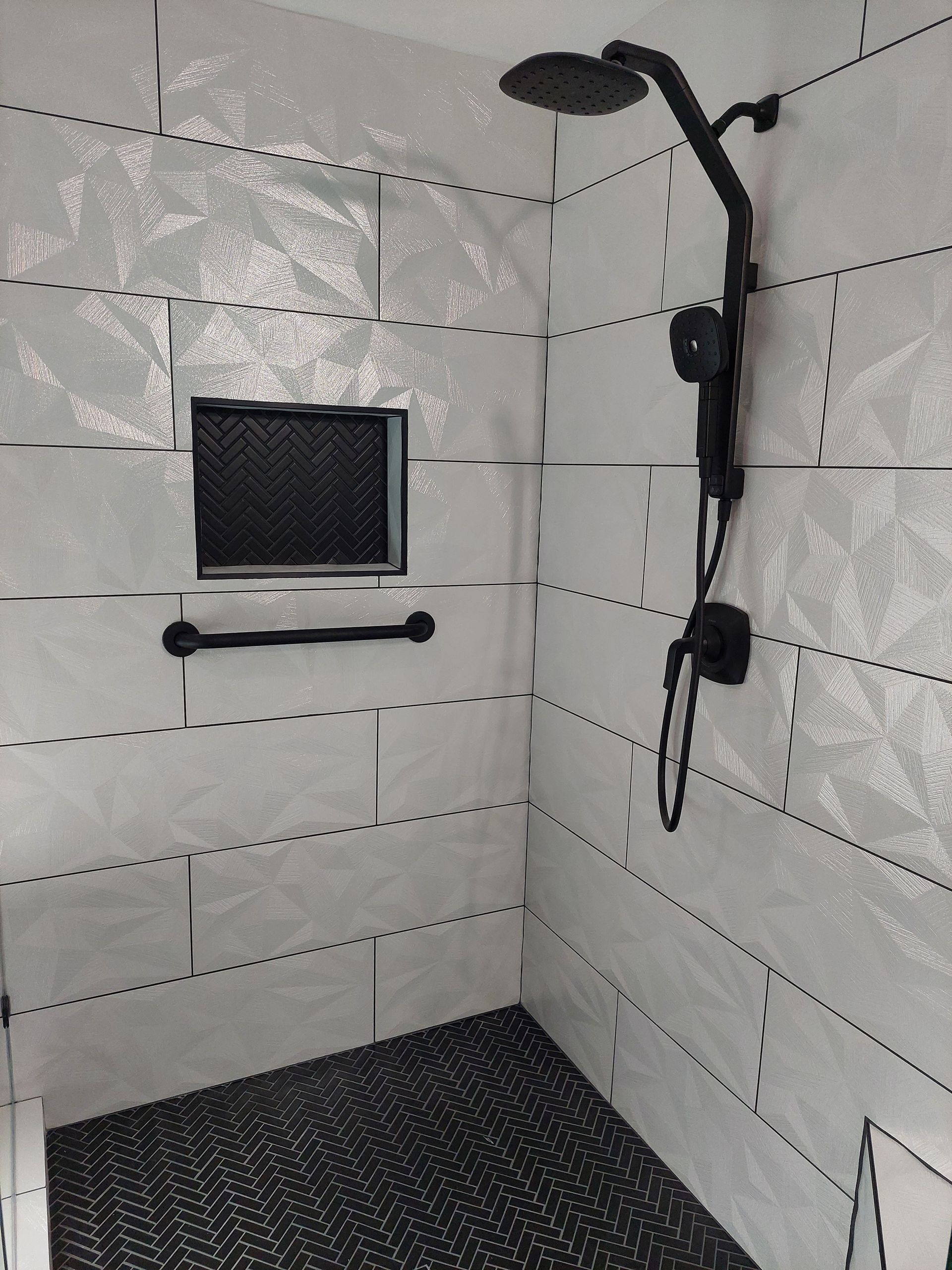a shower with white tiles and a black shower head