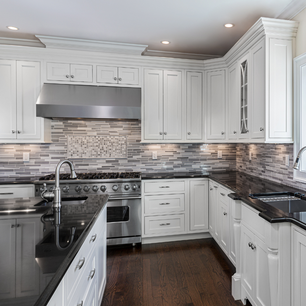 a kitchen with white cabinets and black counter tops