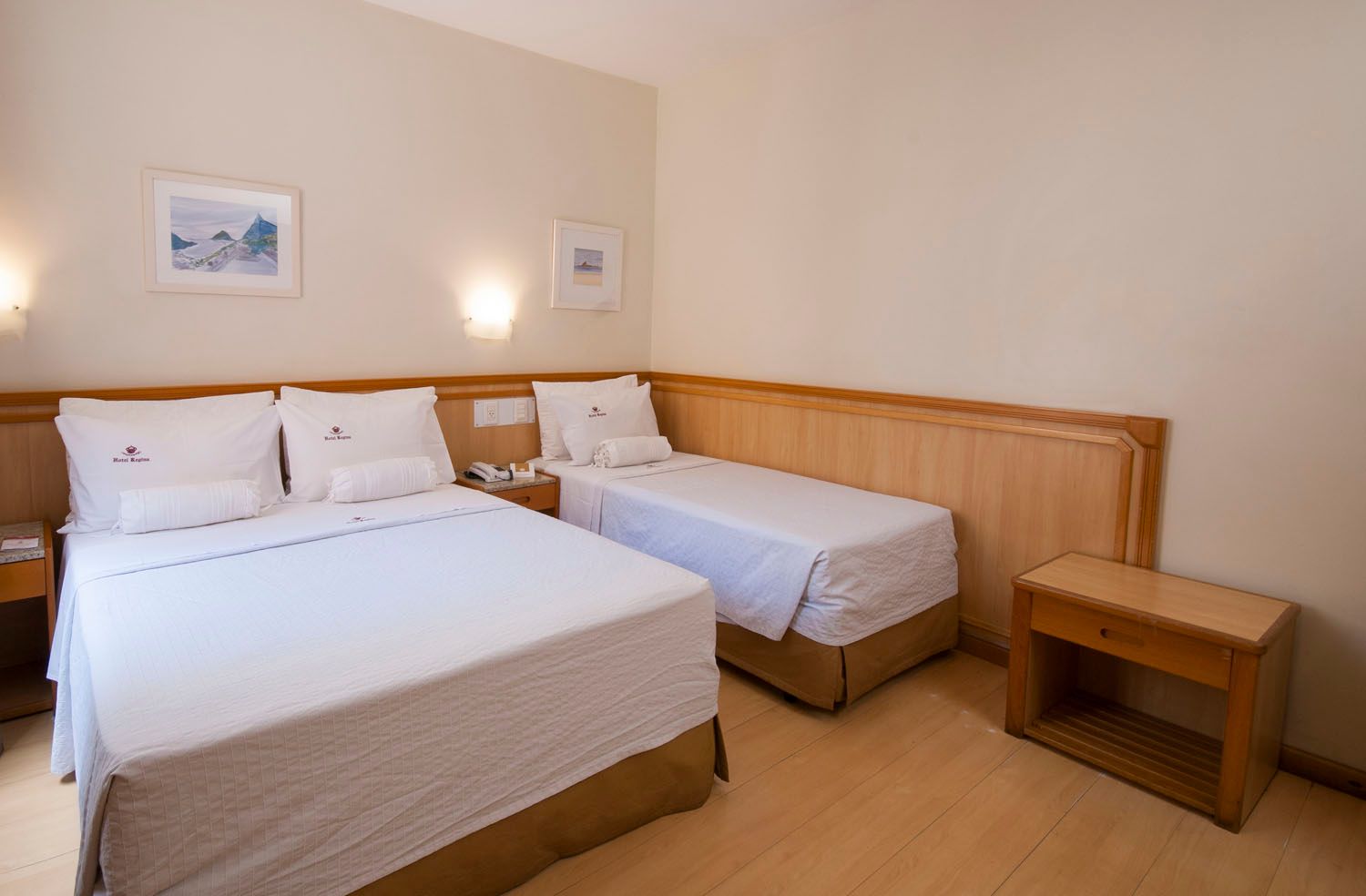 Um quarto de hotel com duas camas e uma mesa de cabeceira.