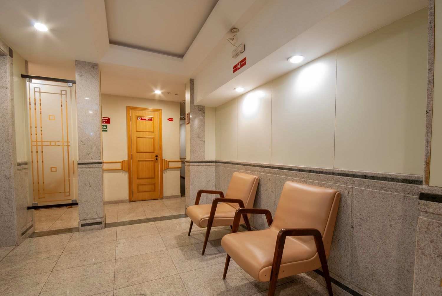 Duas cadeiras estão em um corredor ao lado de uma porta.