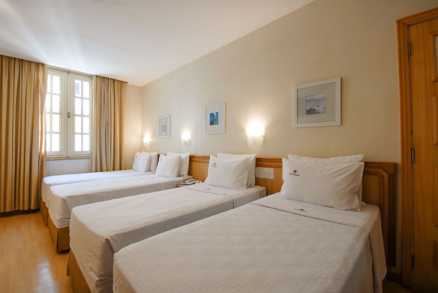 Um quarto de hotel com três camas e uma janela