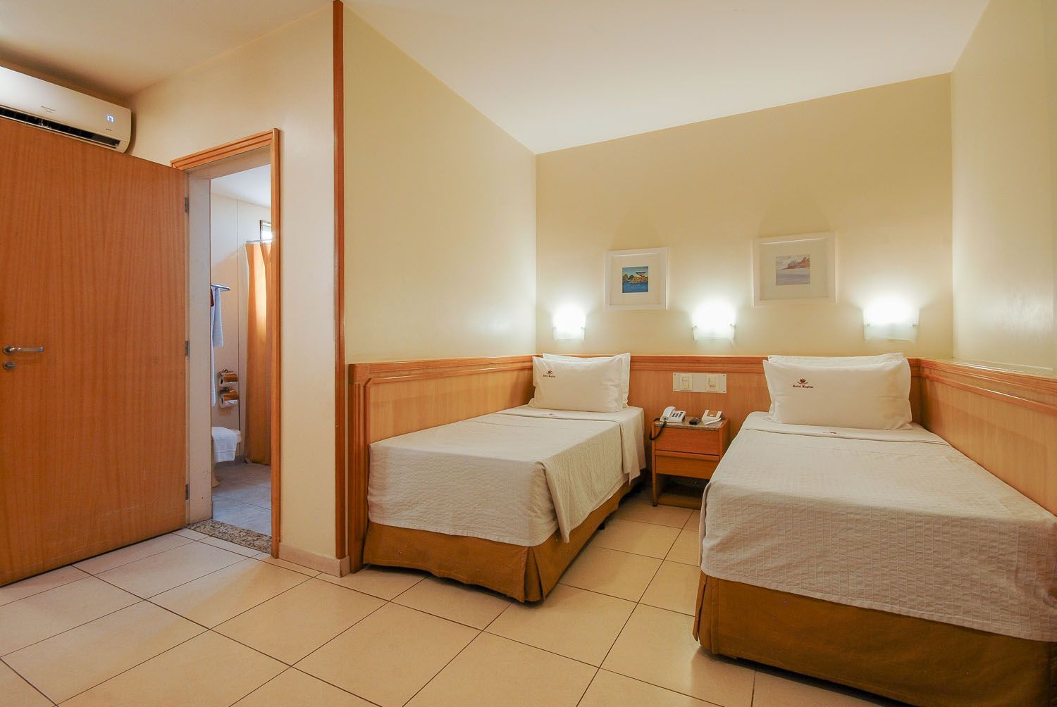 Um quarto de hotel com duas camas e um banheiro.