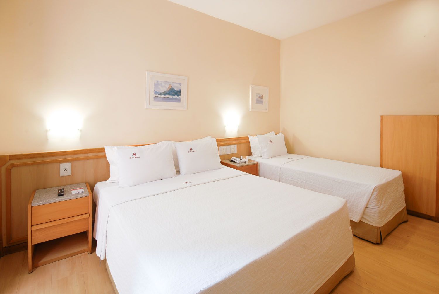 Um quarto de hotel com duas camas e uma mesa de cabeceira.