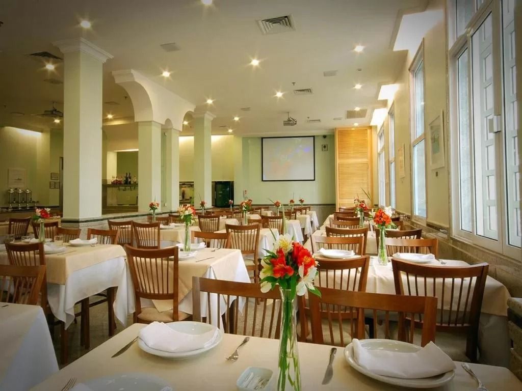 Uma grande sala de jantar com mesas e cadeiras e uma tela de projetor.