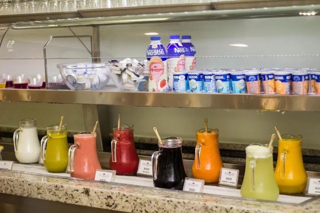 Uma fileira de jarras cheias de diferentes tipos de bebidas estão alinhadas em um balcão.