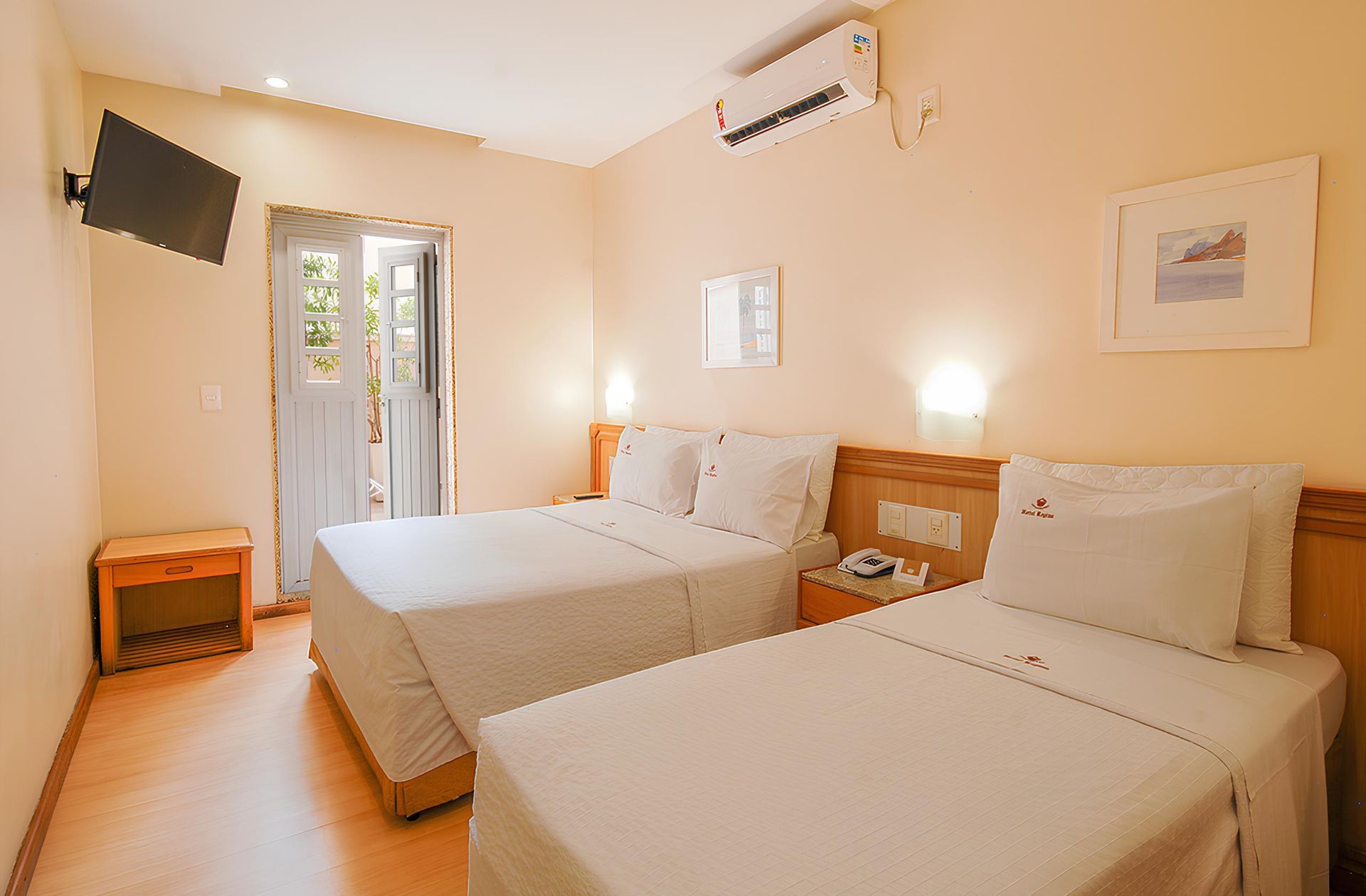 Um quarto de hotel com duas camas e uma TV de tela plana.
