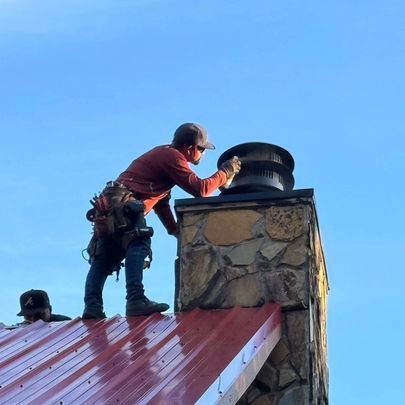A man is working on a chimney on top of a roof
