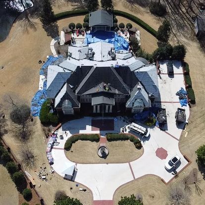 An aerial view of a large house with blue tarps on the roof
