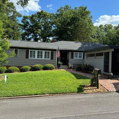 A house with a large lawn and a flag in front of it.