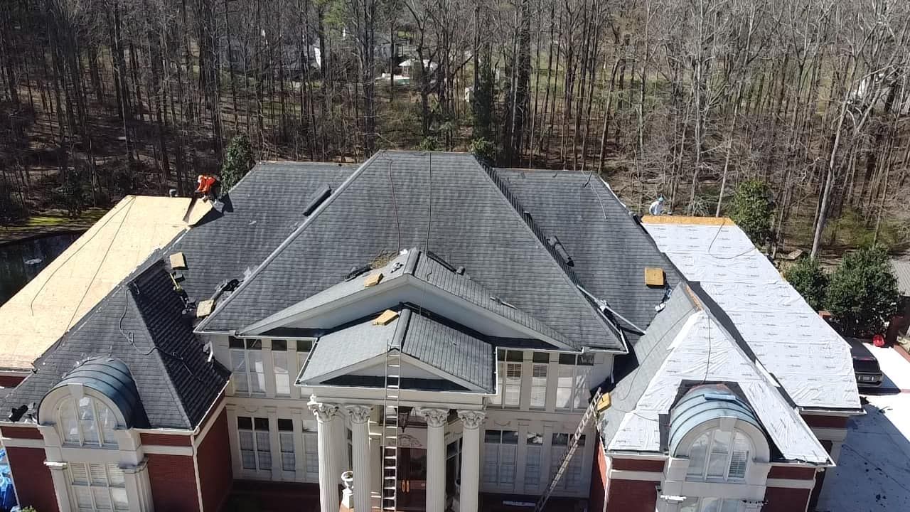 An aerial view of a large house with a roof being installed.