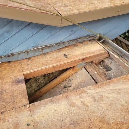 A wooden roof with a hole in it is being repaired.