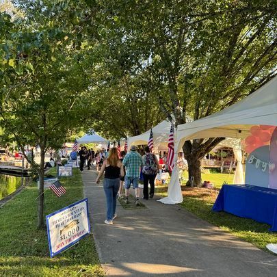 A group of people are walking down a sidewalk in a park.