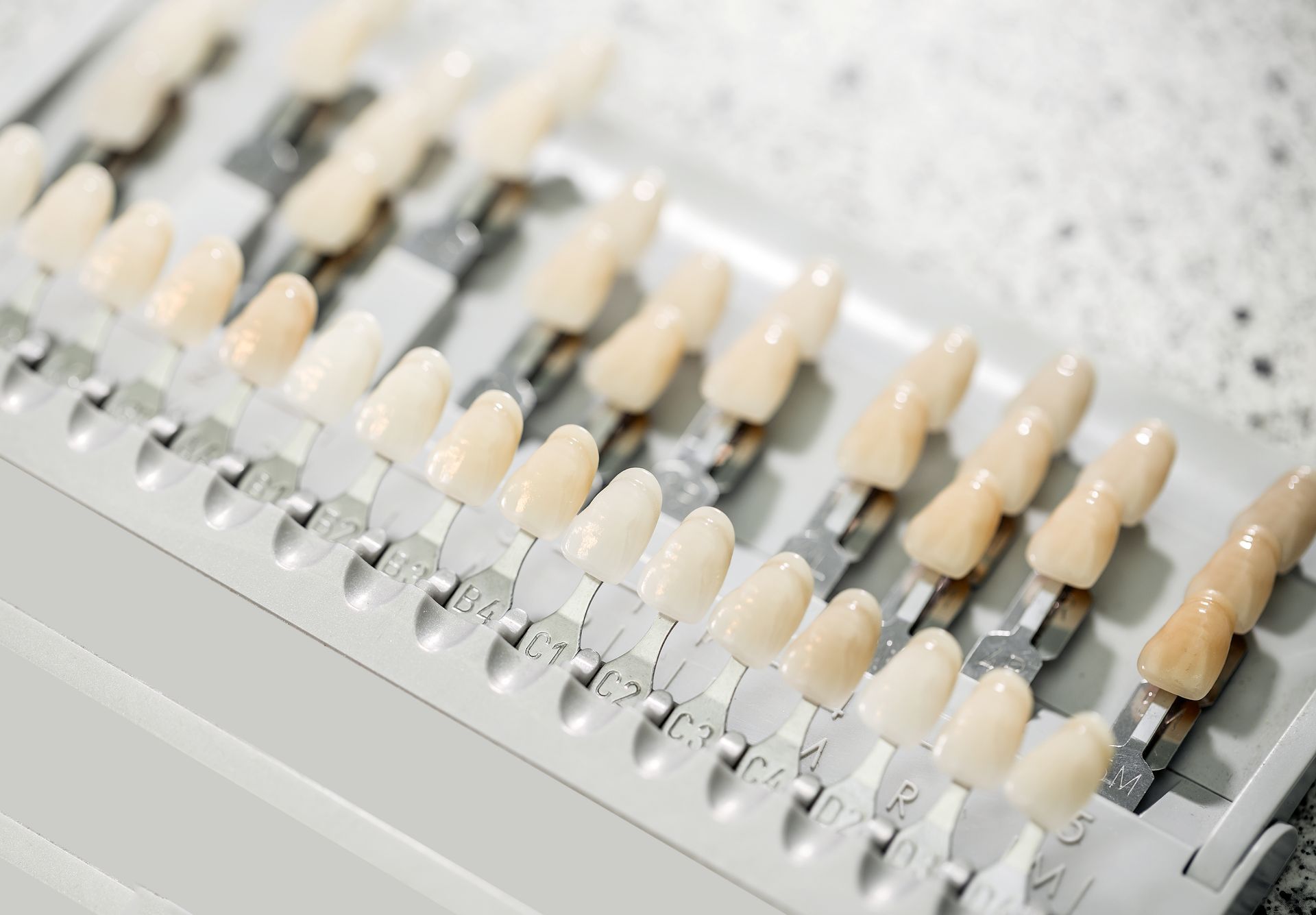 A set of dental veneers tooth shade samples arranged on a table, displaying a variety of colour options for achieving a natural and personalised smile