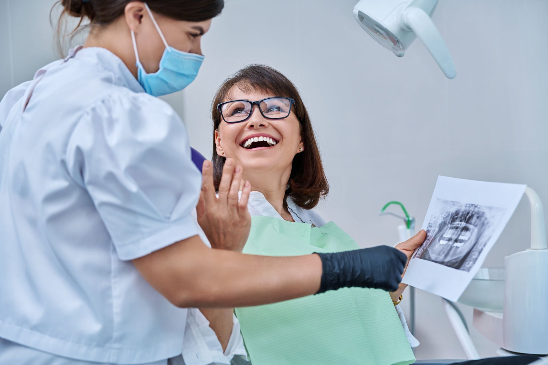 female- dentist talking to woman patient discussing teeth x-ray for wisdom tooth