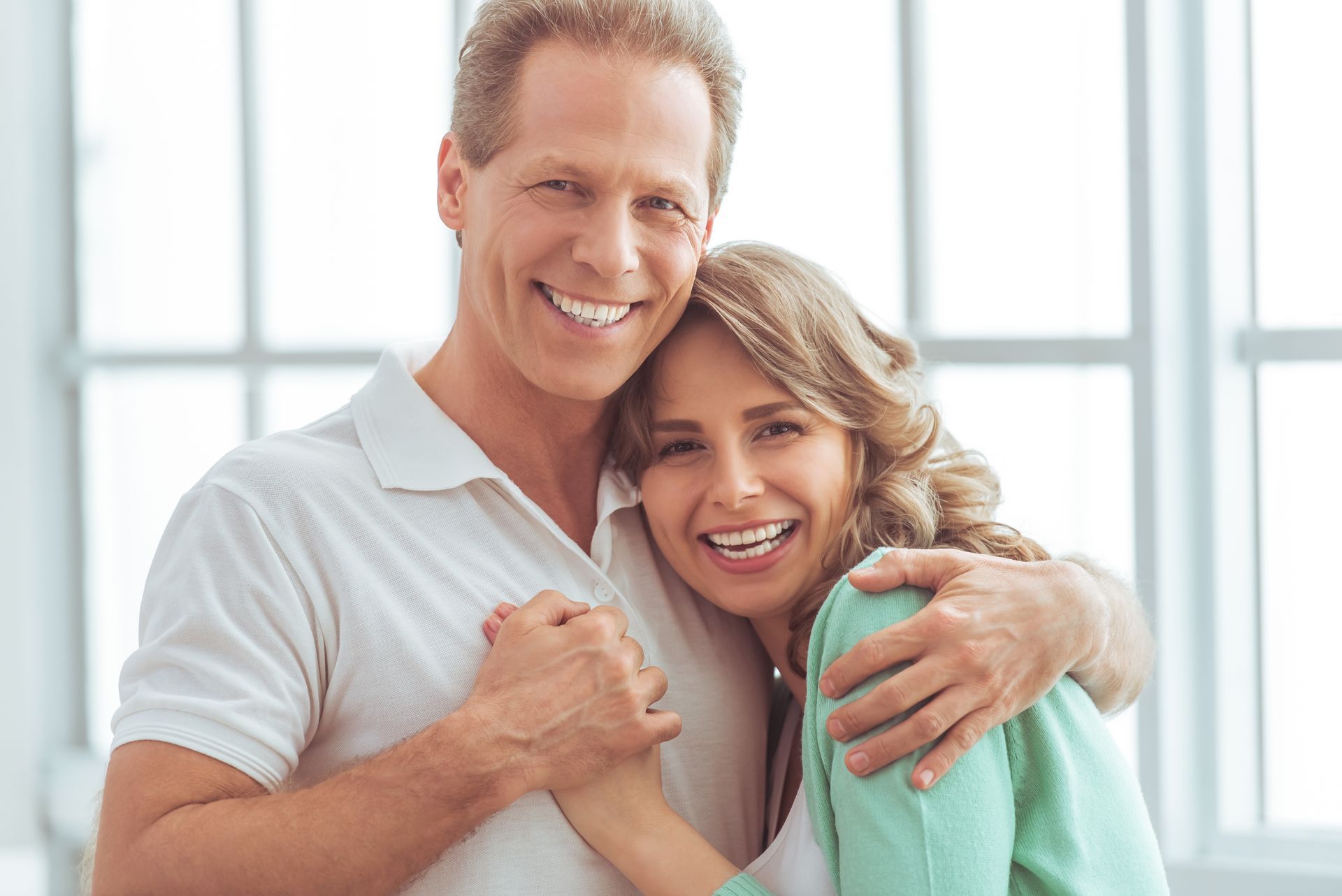 Happy middle-aged couple smiling with confidence after receiving dental implants in Toowoomba.
