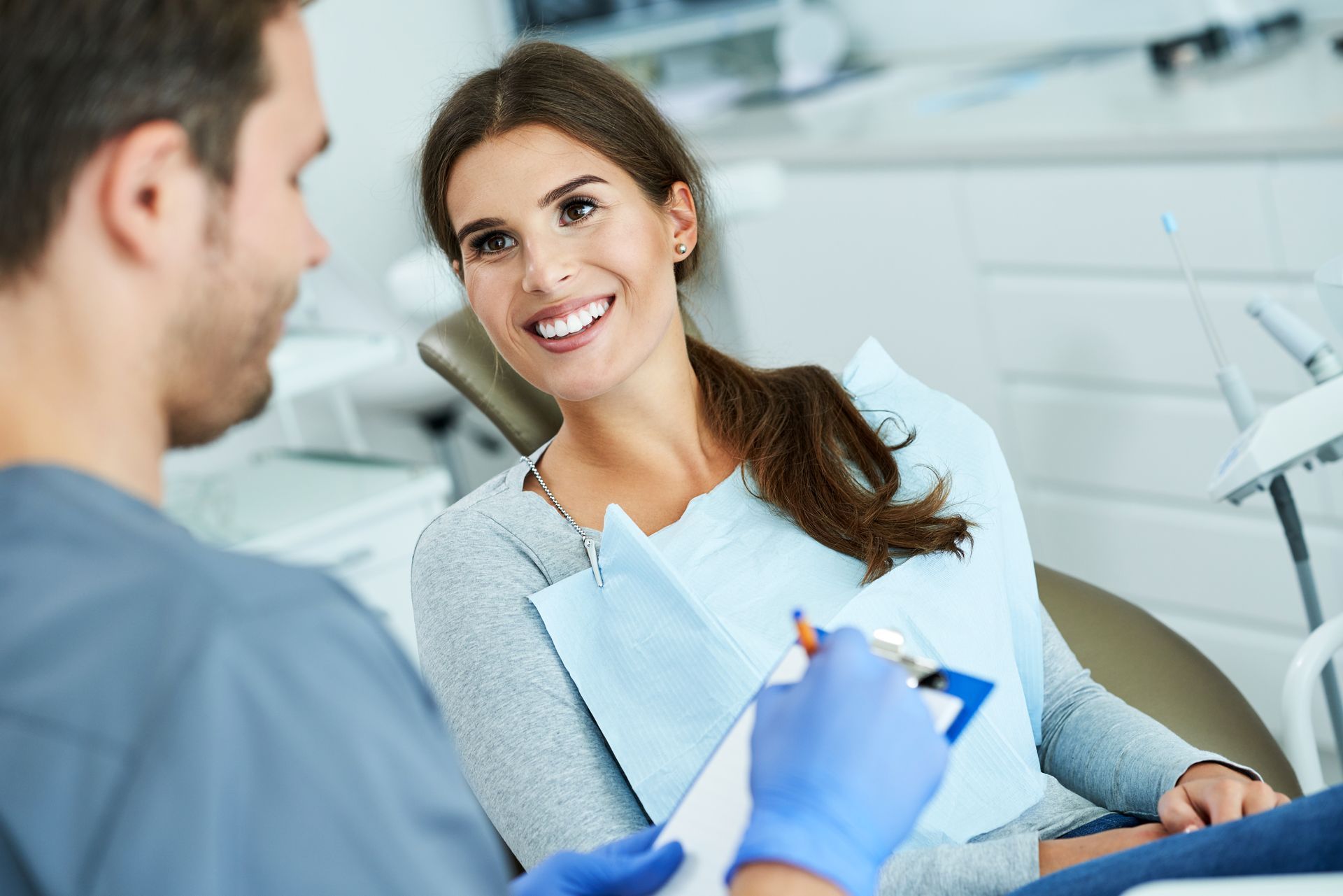 Smiling woman sitting in a dental chair looking at his dentist explaining the dental procedure