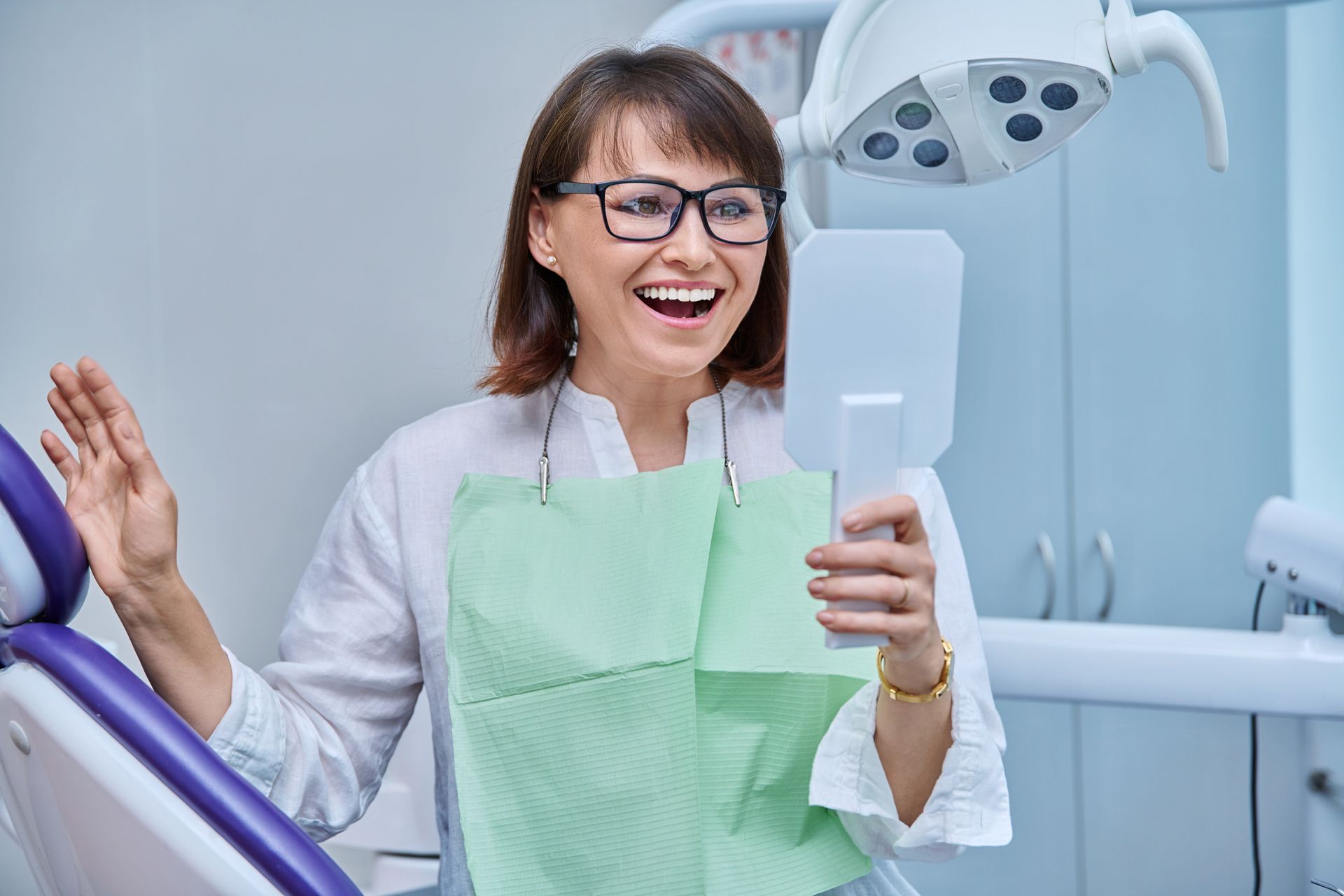 Happy middle-aged woman admiring her new smile after receiving All-on-4 implants in Toowoomba