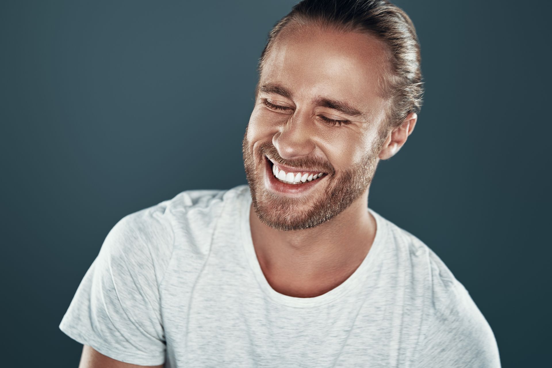 Smiling man in dark blue with a radiant, even smile showing results of veneers in Newtown