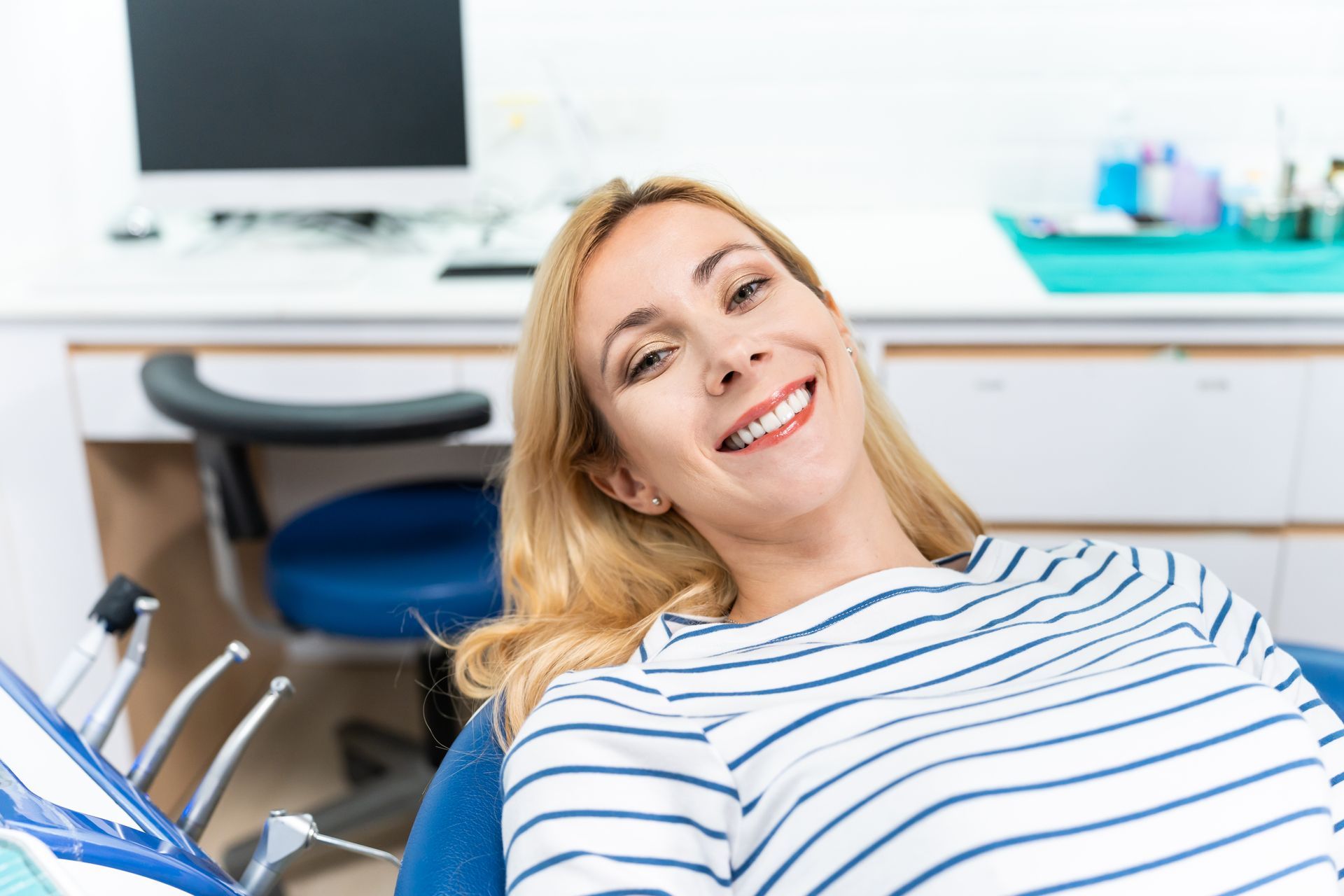 Happy female patient smiling in the dental chair after All-on-4 implant consultation at a Toowoomba dental clinic.