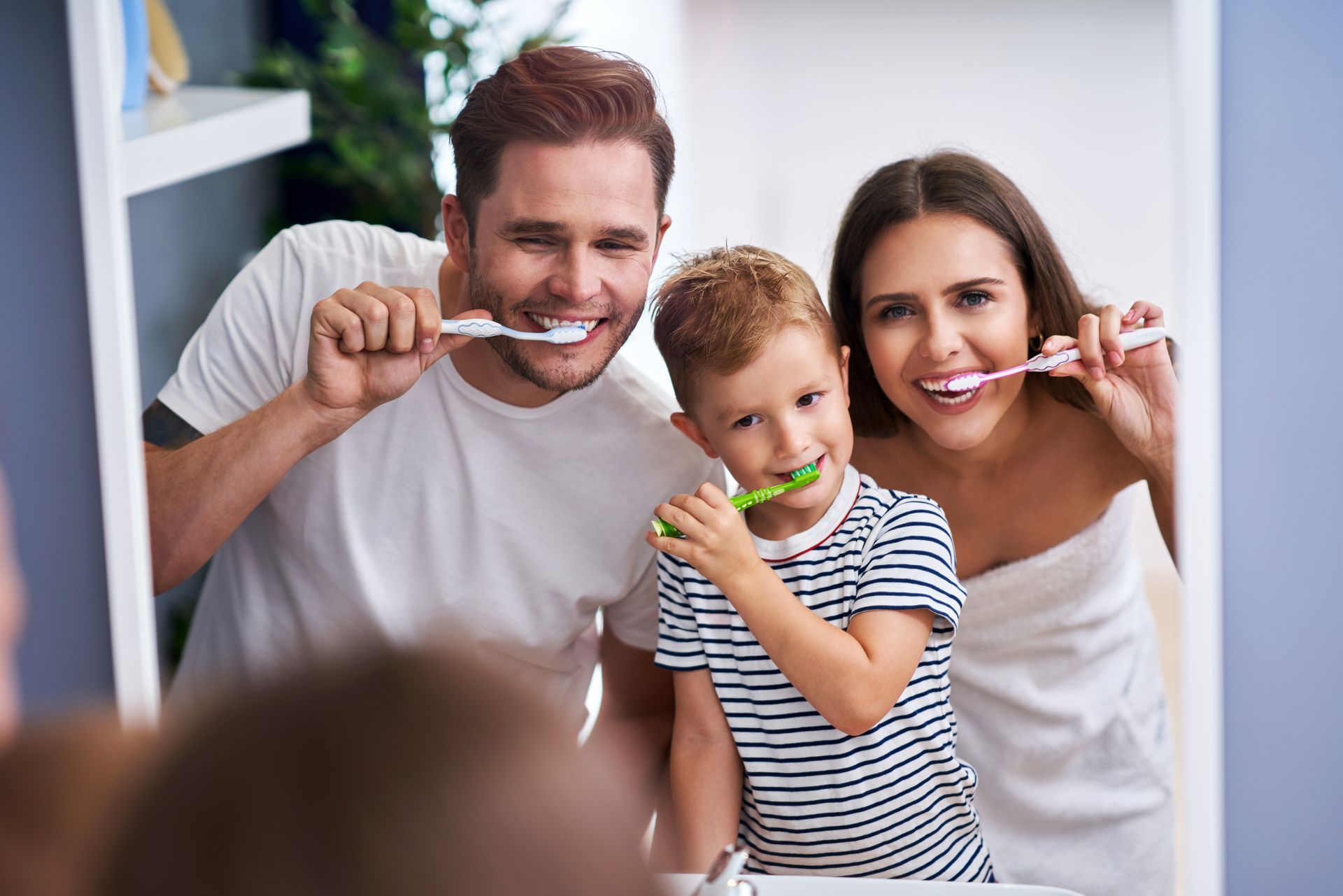 Portrait of happy family brushing teeth in the bathroom