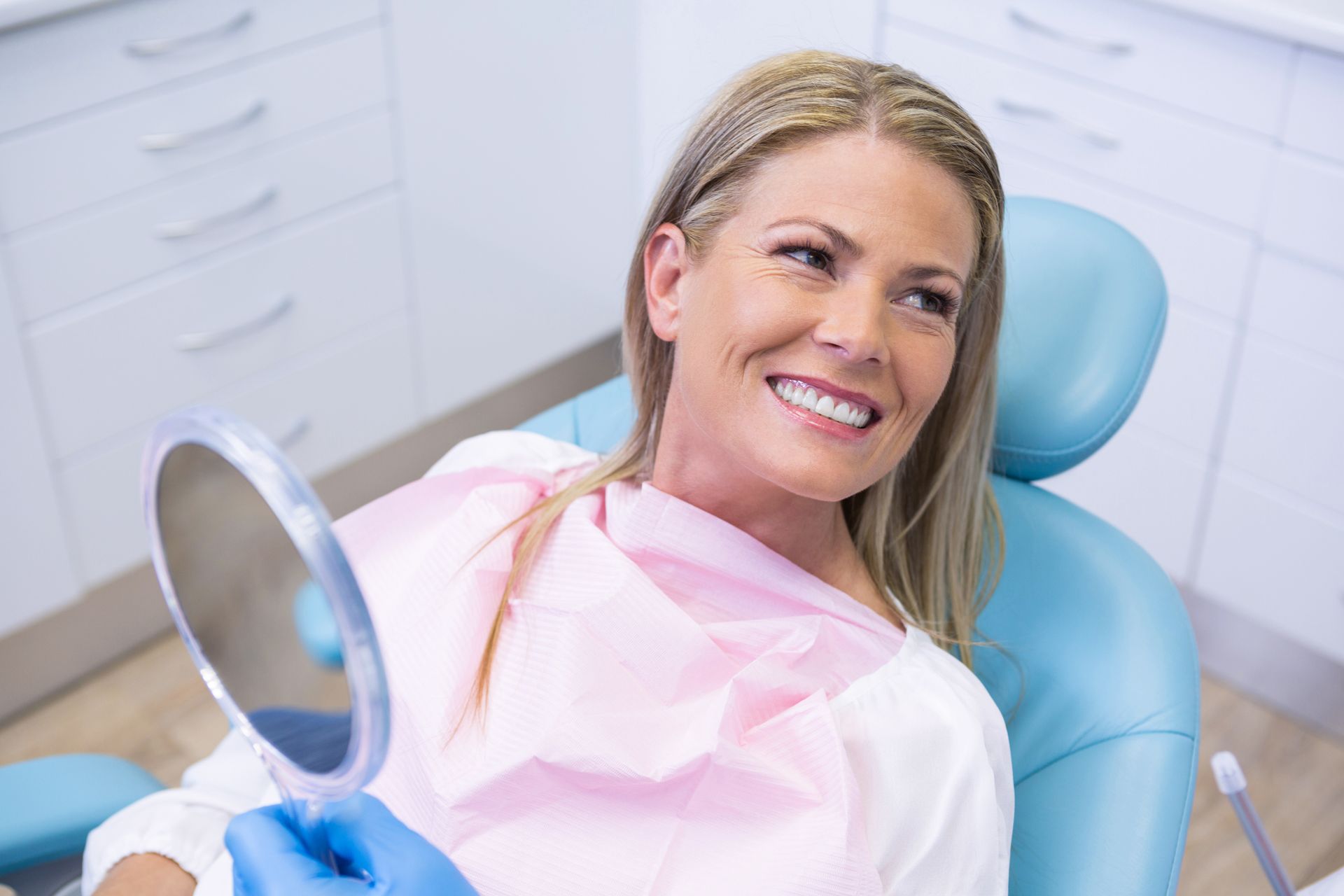 Happy female patient admiring her new smile after receiving All-on-4 dental implants in Toowoomba at Garden City Dental Practice,