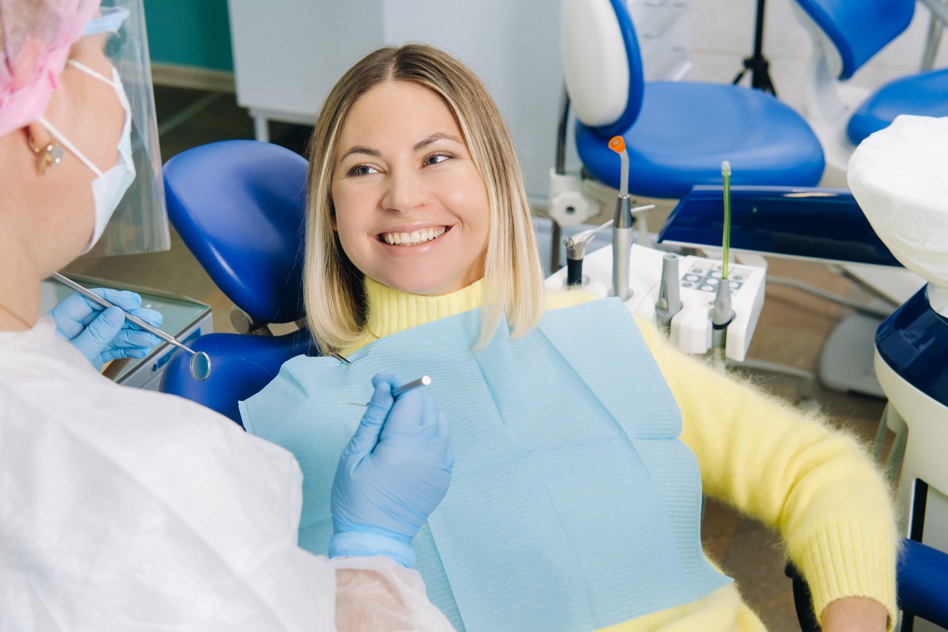 The girl smiles at the dentist and looks at her during dental check up and clean