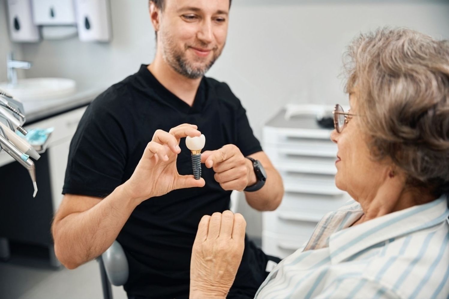 Dentist explaining dental implant structure to senior patient during consultation in Toowoomba